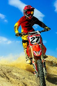 Motocross rider speeding on dirt track, showcasing skill and adrenaline.