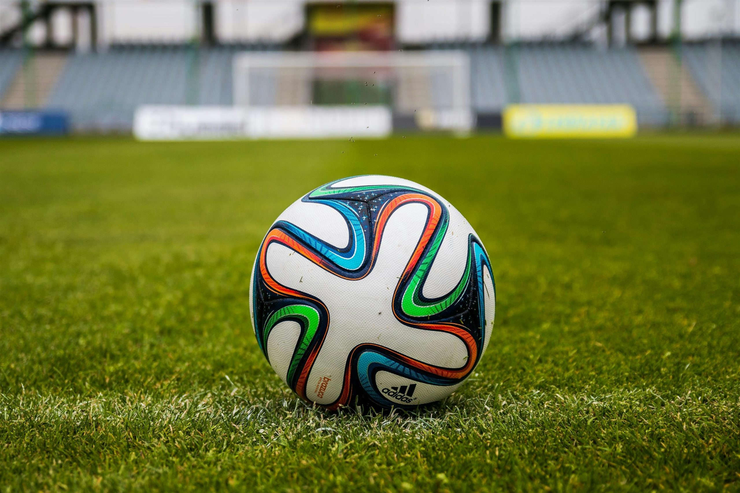 A vibrant adidas soccer ball on a green field, perfect for sports enthusiasts.